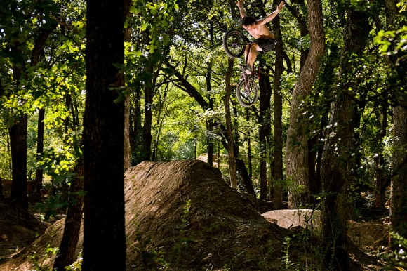 beautiful photo of a guy in mid-flight above a series of dirt jumps